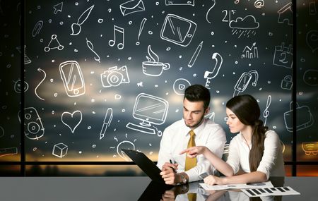 Business couple sitting at table with hand drawn social media icons and symbols