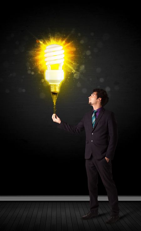 Businessman hold a shining eco-friendly idea bulb on a black background