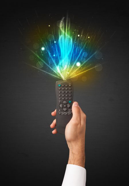 Hand holding a remote control, shining and explosive signal coming out of it