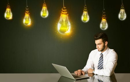 Businessman sitting at the black table with idea bulbs on the background