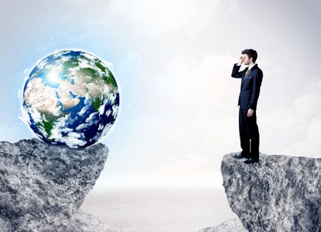 Businessman standing on the edge of mountain with a globe on the other side,""Element of this image furnished by NASA"" 