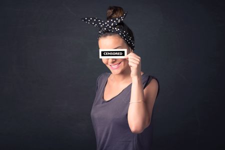 Pretty girl with censored paper sign holding in hand