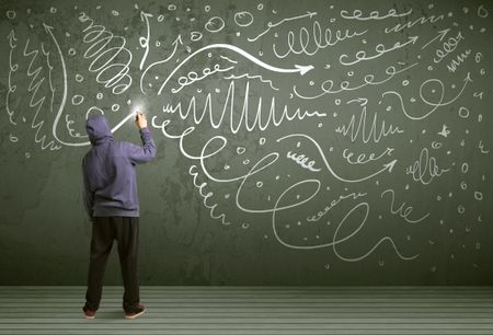 Young urban painter drawing curly lines and arrows on the wall