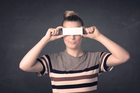 Pretty girl holding blank copy space paper at her eyes concept