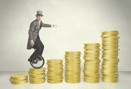 Business man riding monocycle up on coin graph concept on background