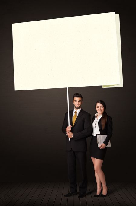 Young business couple holding a big, white post-it paper 