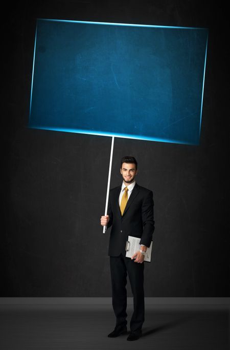 Young businessman holding a big, blue board