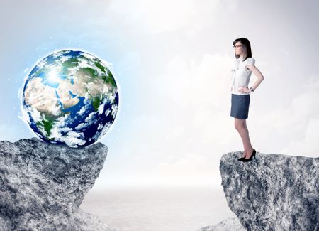Businesswoman standing on the edge of mountain with a globe on the other side, ""Elements of this image furnished by NASA"" 