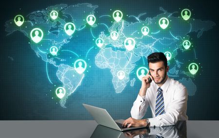 Businessman sitting at table with social media connection symbols on the world map 