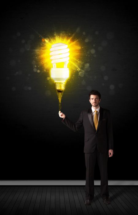 Businessman hold a shining eco-friendly idea bulb on a black background