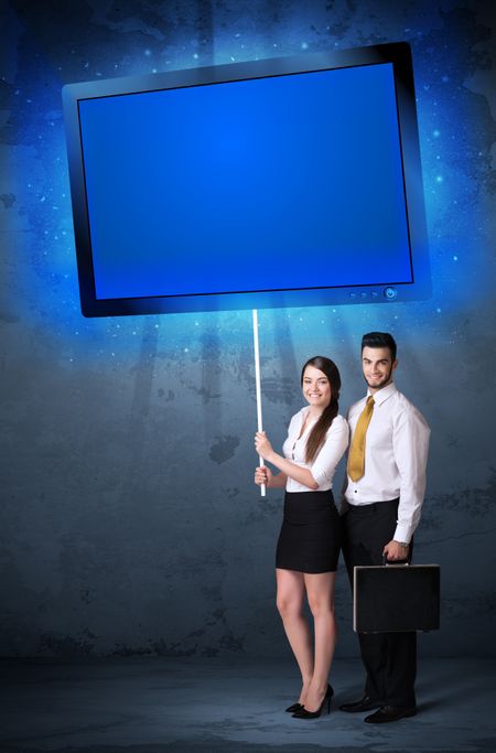 Young business couple holding a big, blue shining tablet