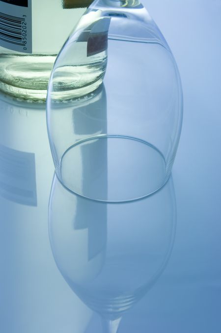 Bottle of white wine, crystal glass, and upside-down reflections of both