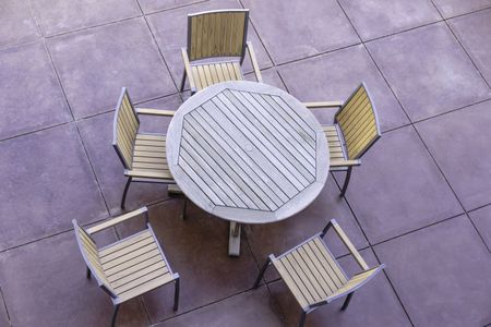 Geometric patterns for casual conversation outdoors: High angle view of wooden round table and five outdoor chairs on large flagstone patio in the American Southwest