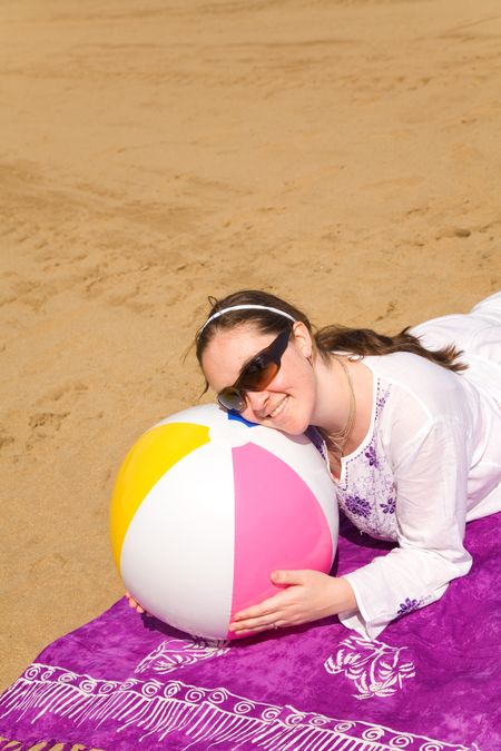 beautiful girl posing with a beach ball on the sand