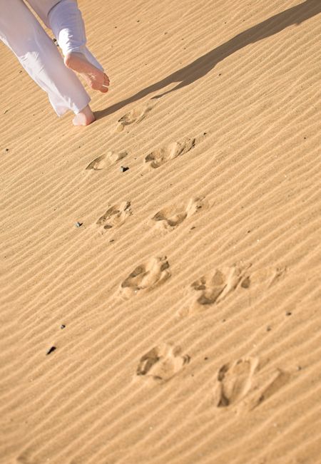 girl waking on the beach leaving footprints on the sand