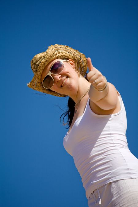 beach girl giving a thumbs up with a smile on her face over a blue sky