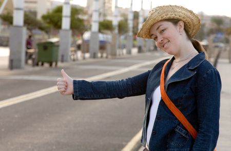 girl hitchhiking on the street with a friendly face wearing a hat