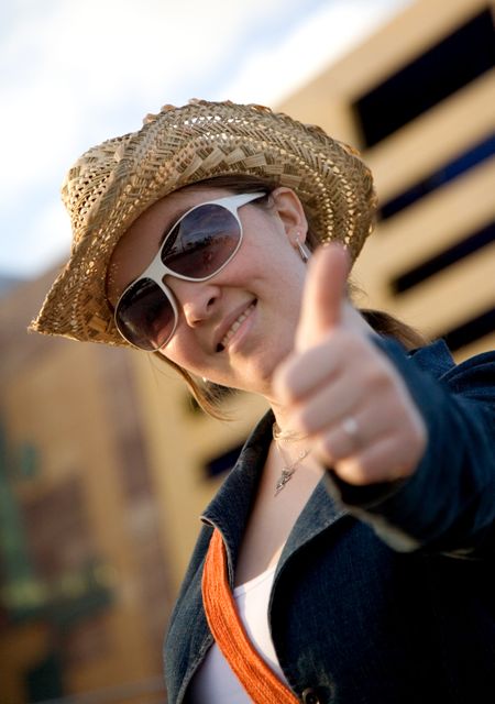 female tourist with thumbs up wearing a hat outdoors