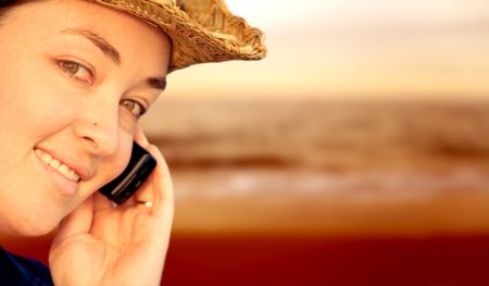 Girl on mobile phone by the beach at sunset time