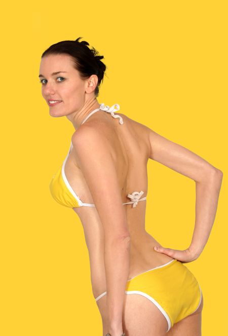 beautiful bikini girl posing over a yellow background