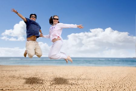 couple in love jumping of joy at the beach on a sunny day