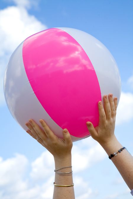 beach ball held by female hands over a blue sky