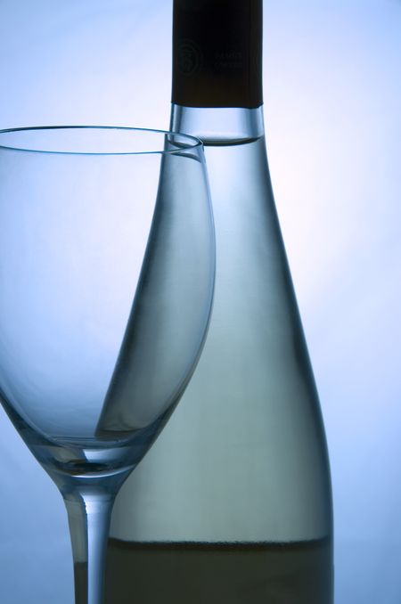 Empty wine glass by unopened bottle of white wine