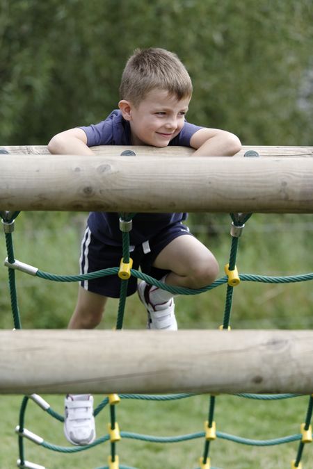 Young boy having fun climbing an assault course