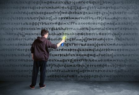 Young urban painter drawing random letters on the wall 