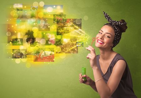 Cute girl blowing colourful glowing memory picture concept on green background