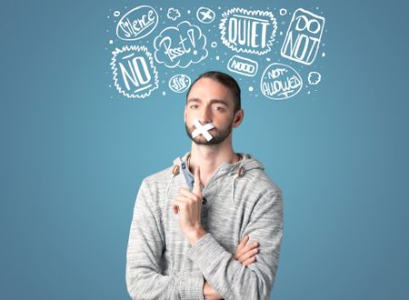 Young man with taped mouth and white drawn thought clouds around his head