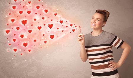 Pretty young girl blowing valentine red heart symbols 