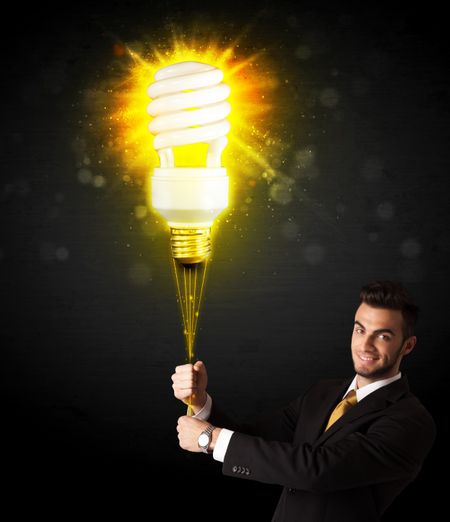 Businessman hold a shining eco-friendly idea bulb on a black background