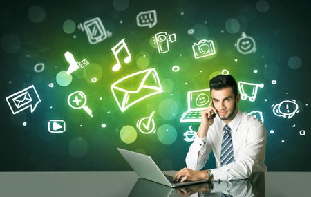 Businessman sitting at the black table with social media symbols on the background 