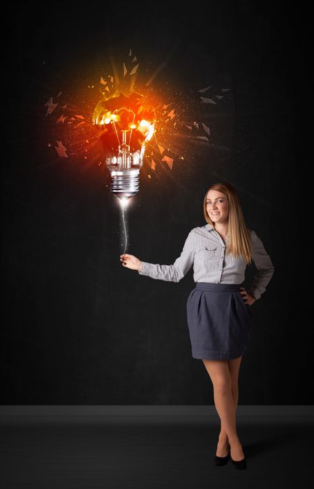 Businesswoman with an explosion bulb on black background