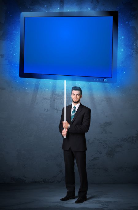 Young businessman holding a big, blue shining tablet
