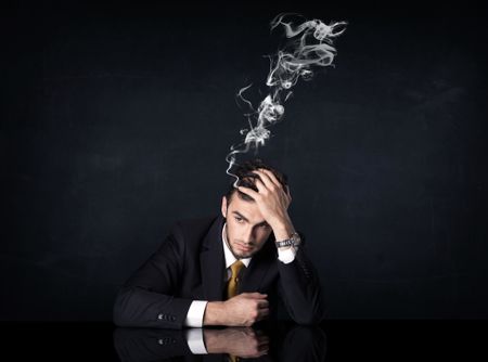Young depressed businessman sitting with smoking head