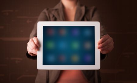 Young woman holding a white tablet with blurry apps