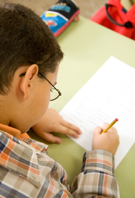boy in primary school education answering a test - focus is on the glasses and eyelashes