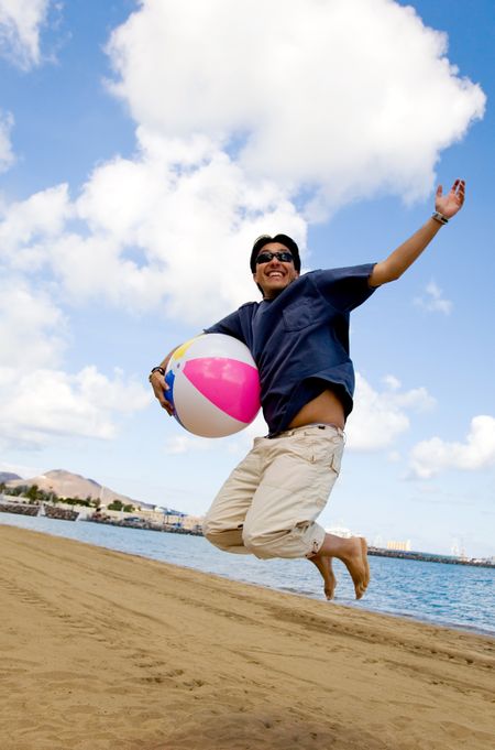 young man having joy at the beach with a beachball