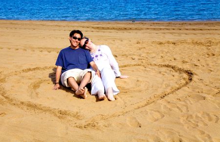 beautiful couple at the beach inside a heartshape