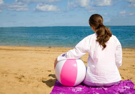 girl relaxing at the beach with a beach ball