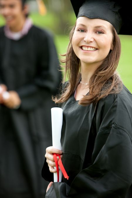 Smily female graduate standing outdoors with her diploma