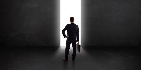 Business person looking at wall with light tunnel opening concept