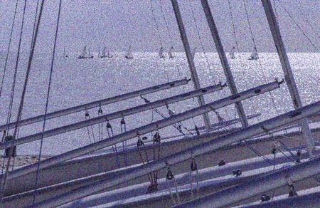 Abstract maritime study: Pointillist view of masts and rigging of beached sailboats in the foreground, with sailboats performing maneuvers during a sailing class on Lake Michigan beyond