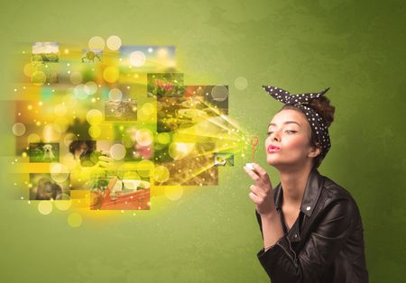 Cute girl blowing colourful glowing memory picture concept on green background