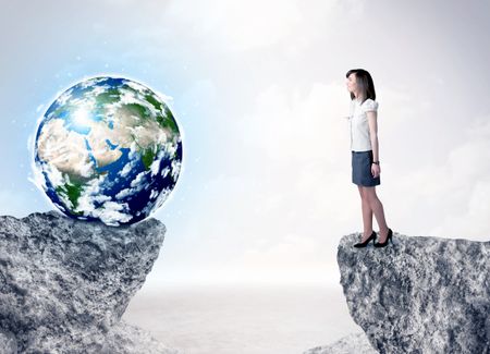 Businesswoman standing on the edge of mountain with a globe on the other side, ""Elements of this image furnished by NASA"" 