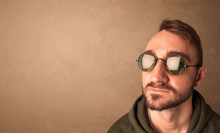 Portrait of a young pretty man with sunglasses and copyspace on brown background