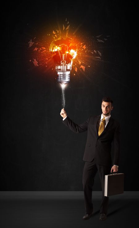 Businessman with an explosion bulb on black background