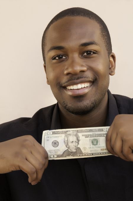 Smiling young black man holding $20 bill